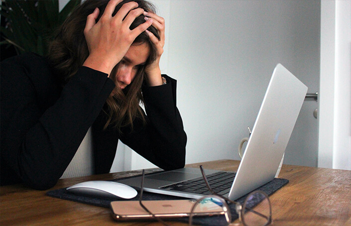 Femme qui stress et se tient la tête devant un ordinateur